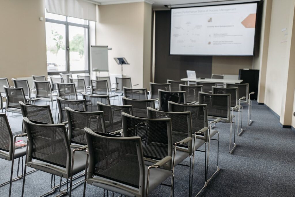 The Art of Drawing Readers In: Your attractive post title goes here Spacious empty conference room with arranged chairs, screen, and natural light for professional meetings.