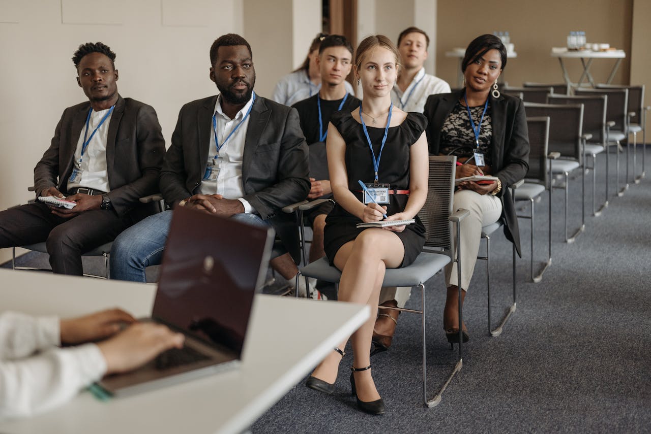 our-journey-03 Diverse group of business professionals attentively attending a conference session.